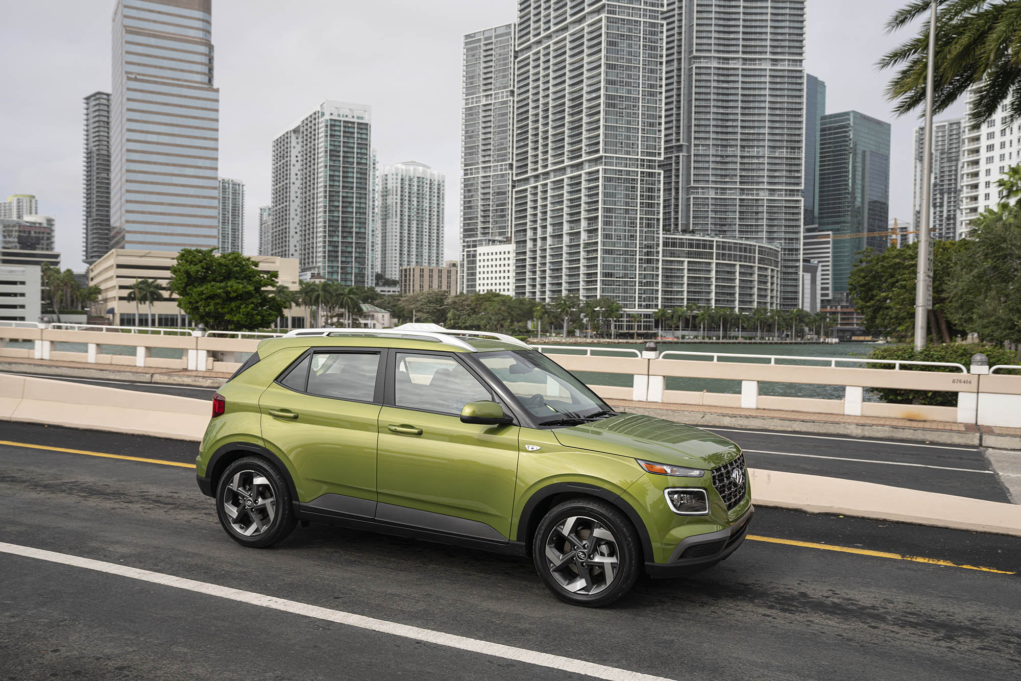 Green Hyundai Venue driving in urban setting