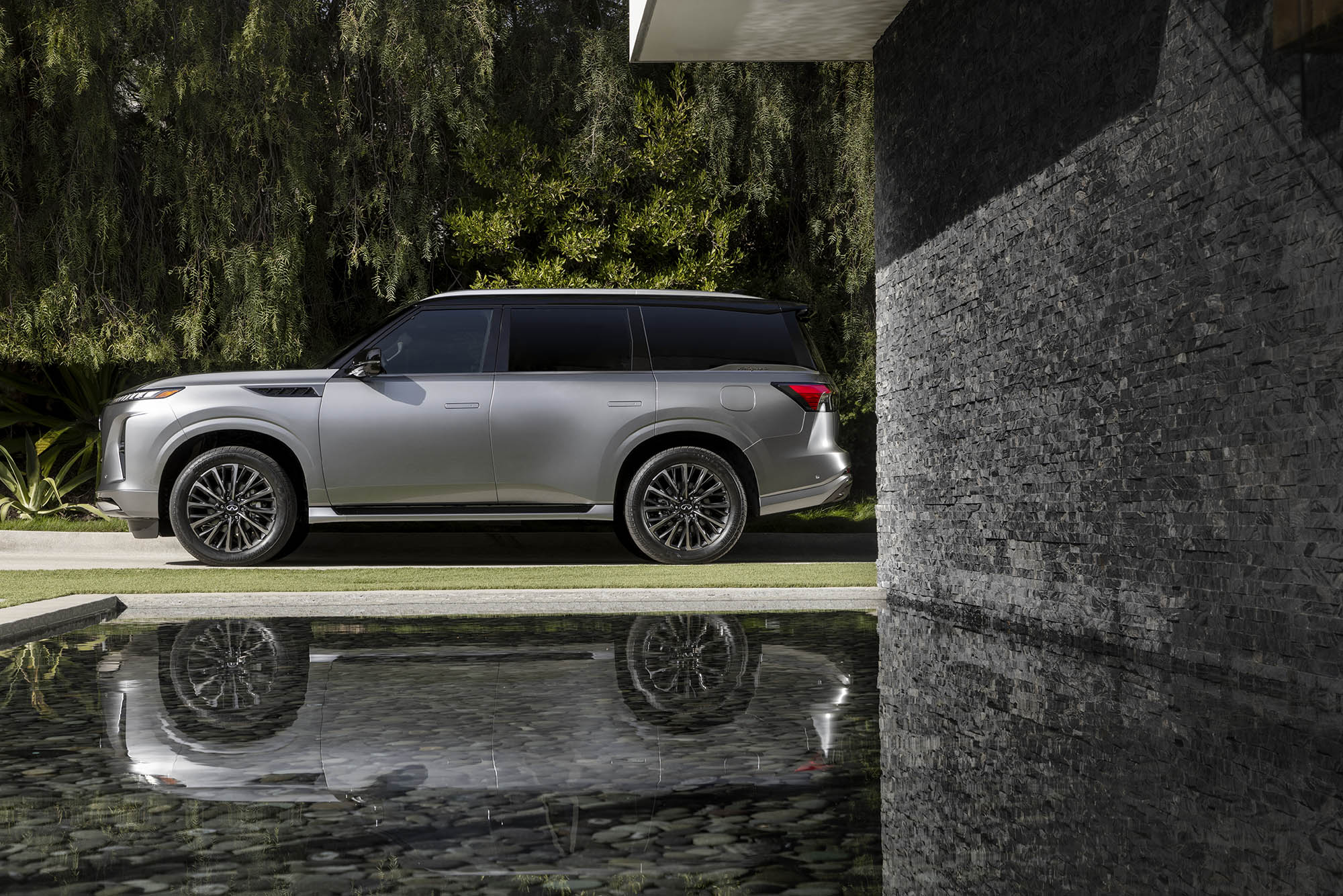 2025 Infiniti QX80 in gray, side profile view with pond reflection below