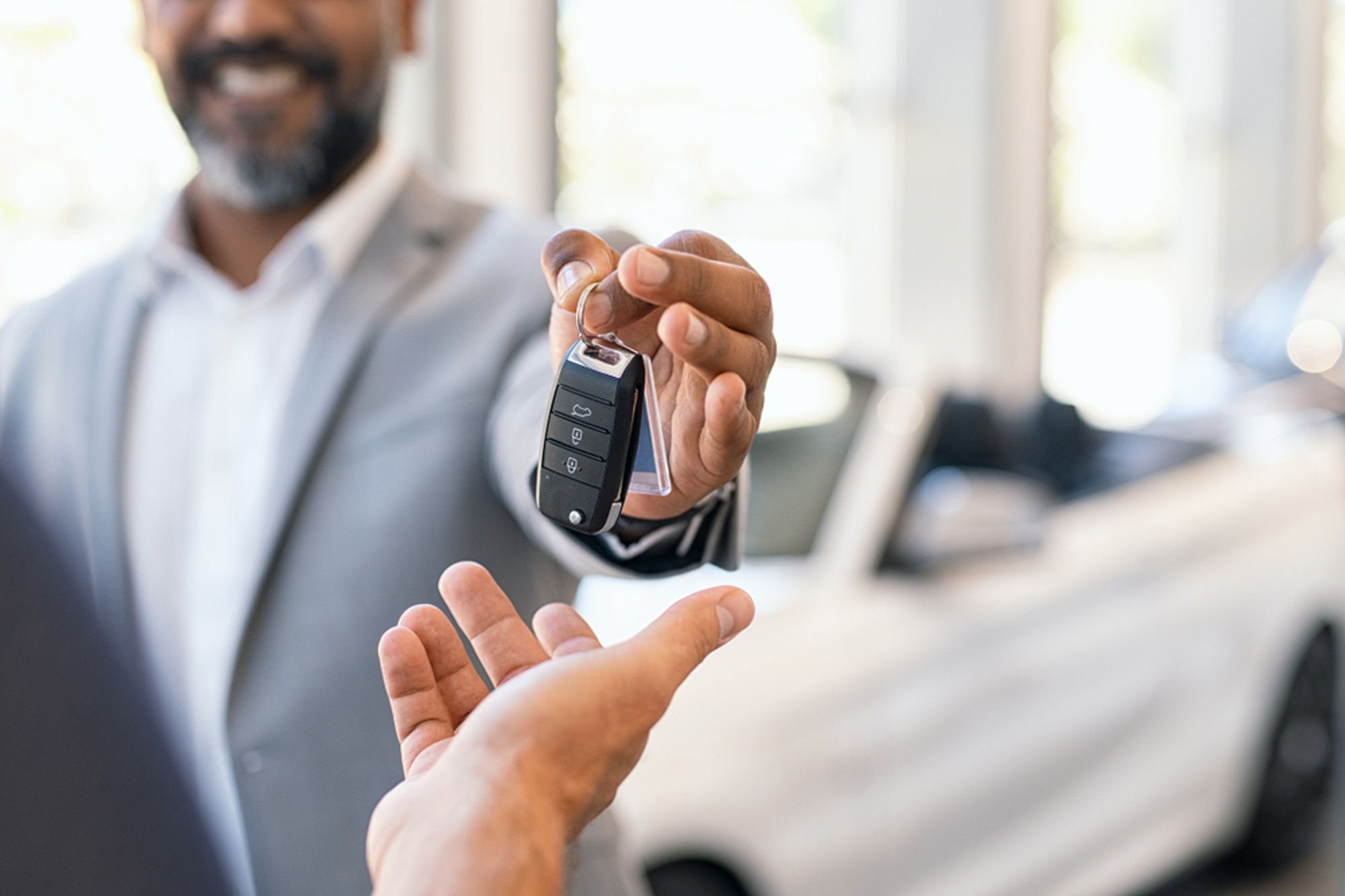 A car dealer hands a buyer the keys to their new vehicle