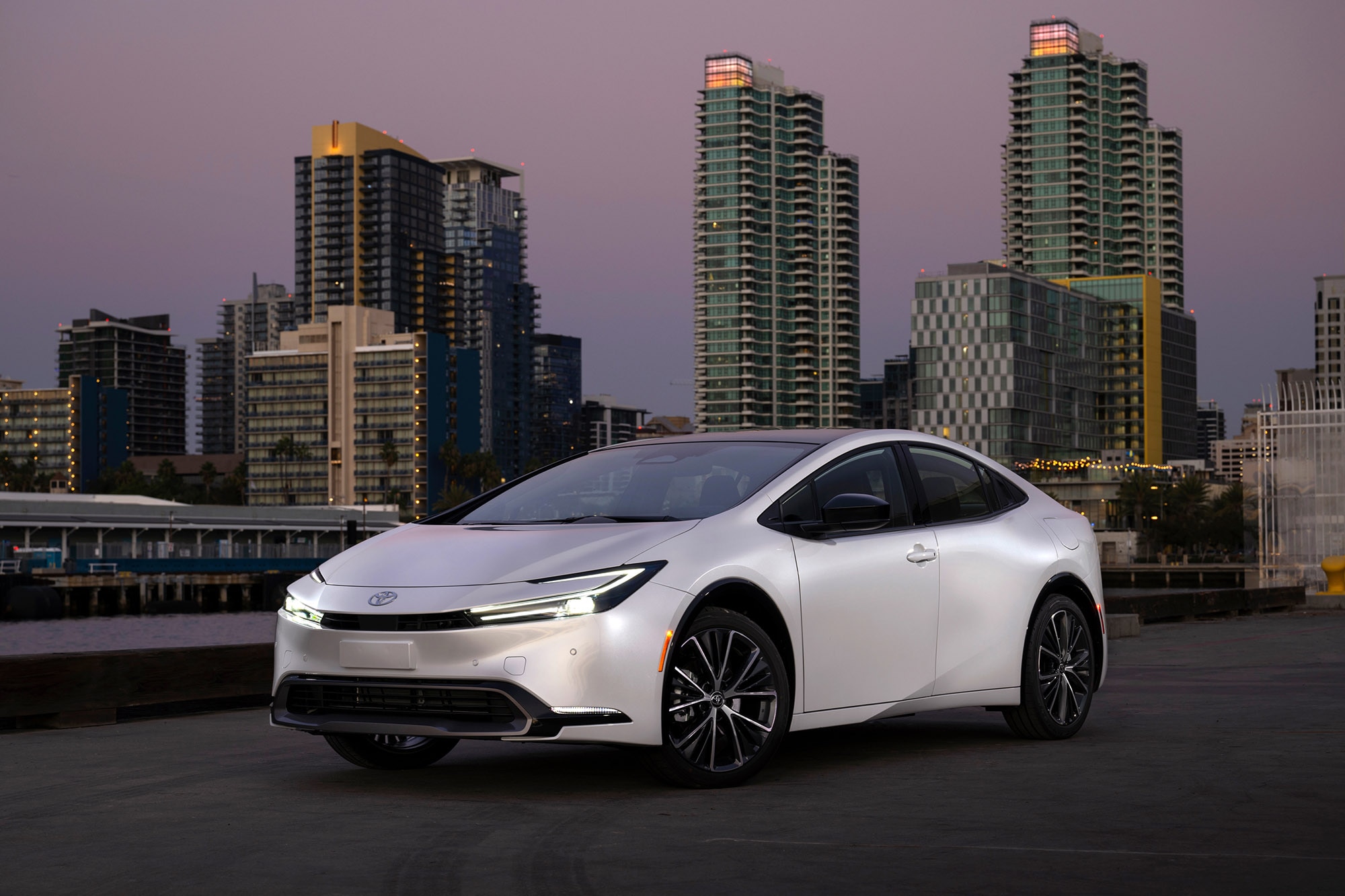 A white 2024 Toyota Prius in front of a cityscape