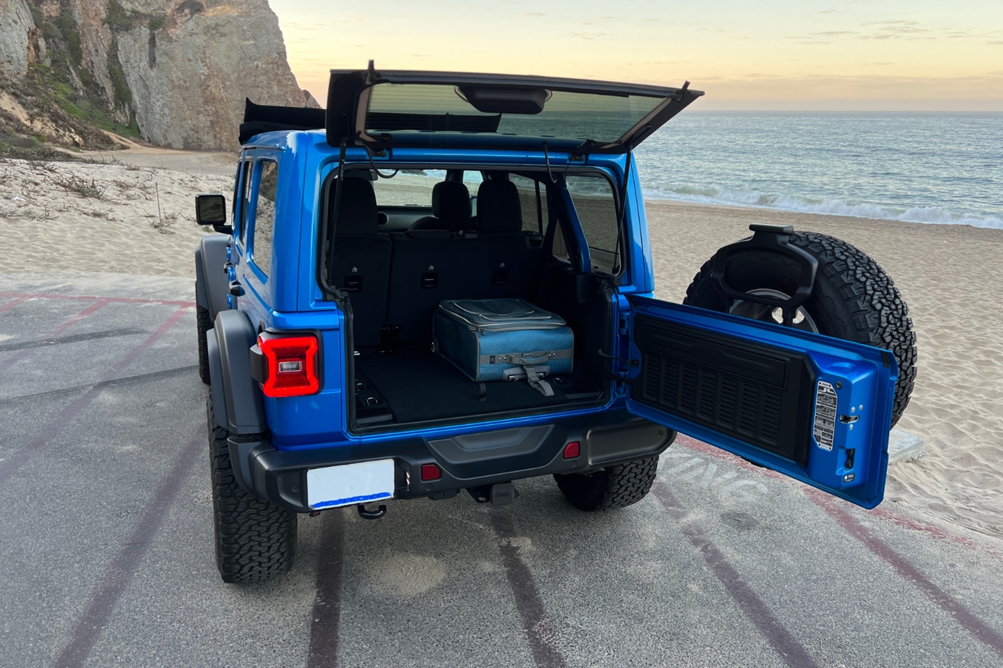 2022 Jeep Wrangler High Tide blue open cargo area parked next to sand and ocean