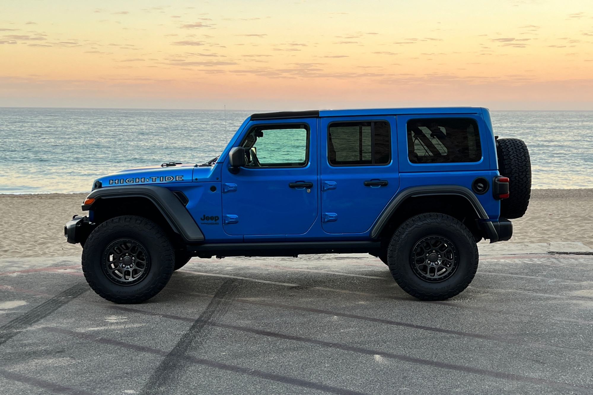 2022 Jeep Wrangler High Tide blue side view parked in front of sand and ocean
