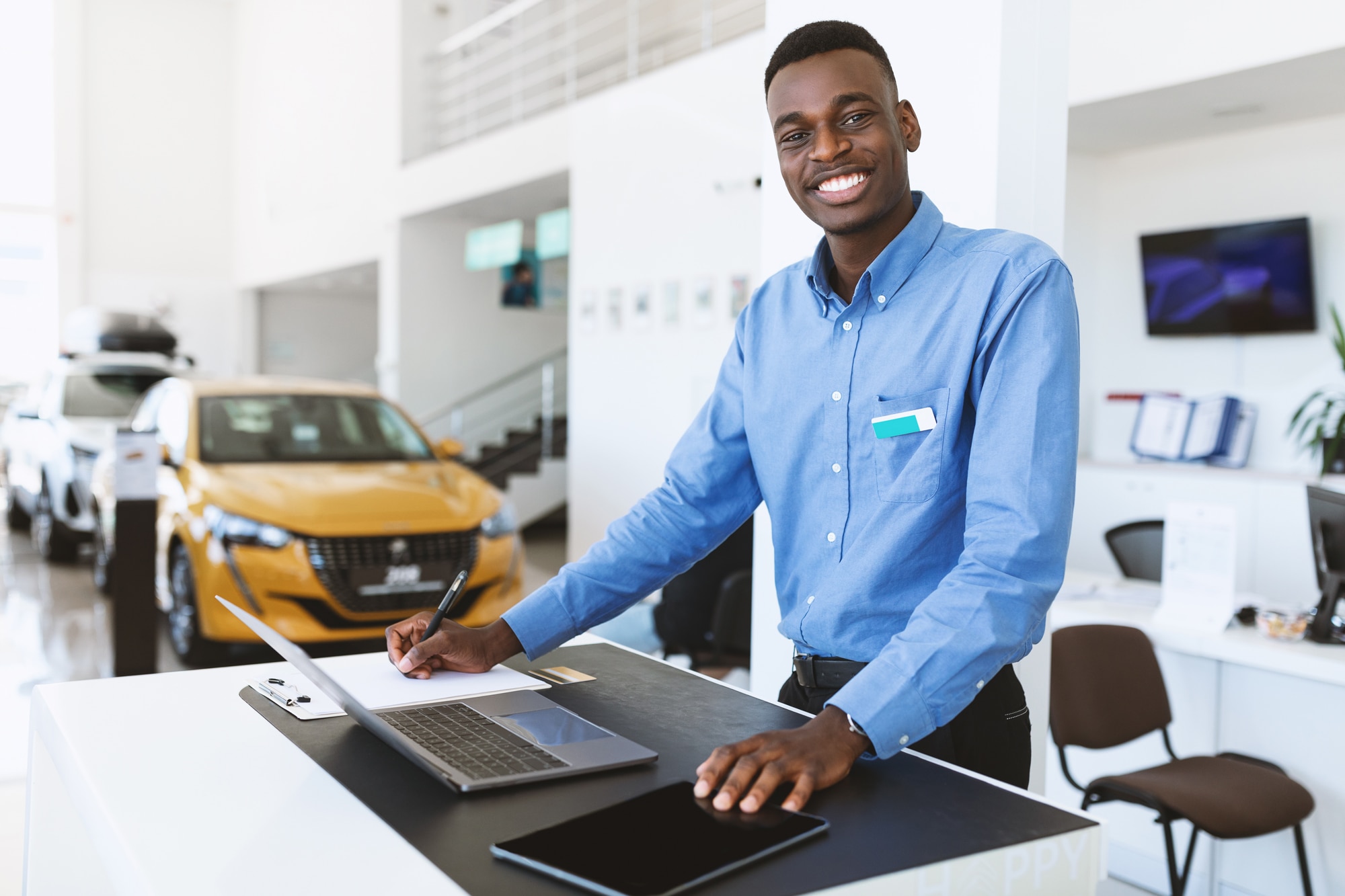 Black car salesman smiling in car dealership