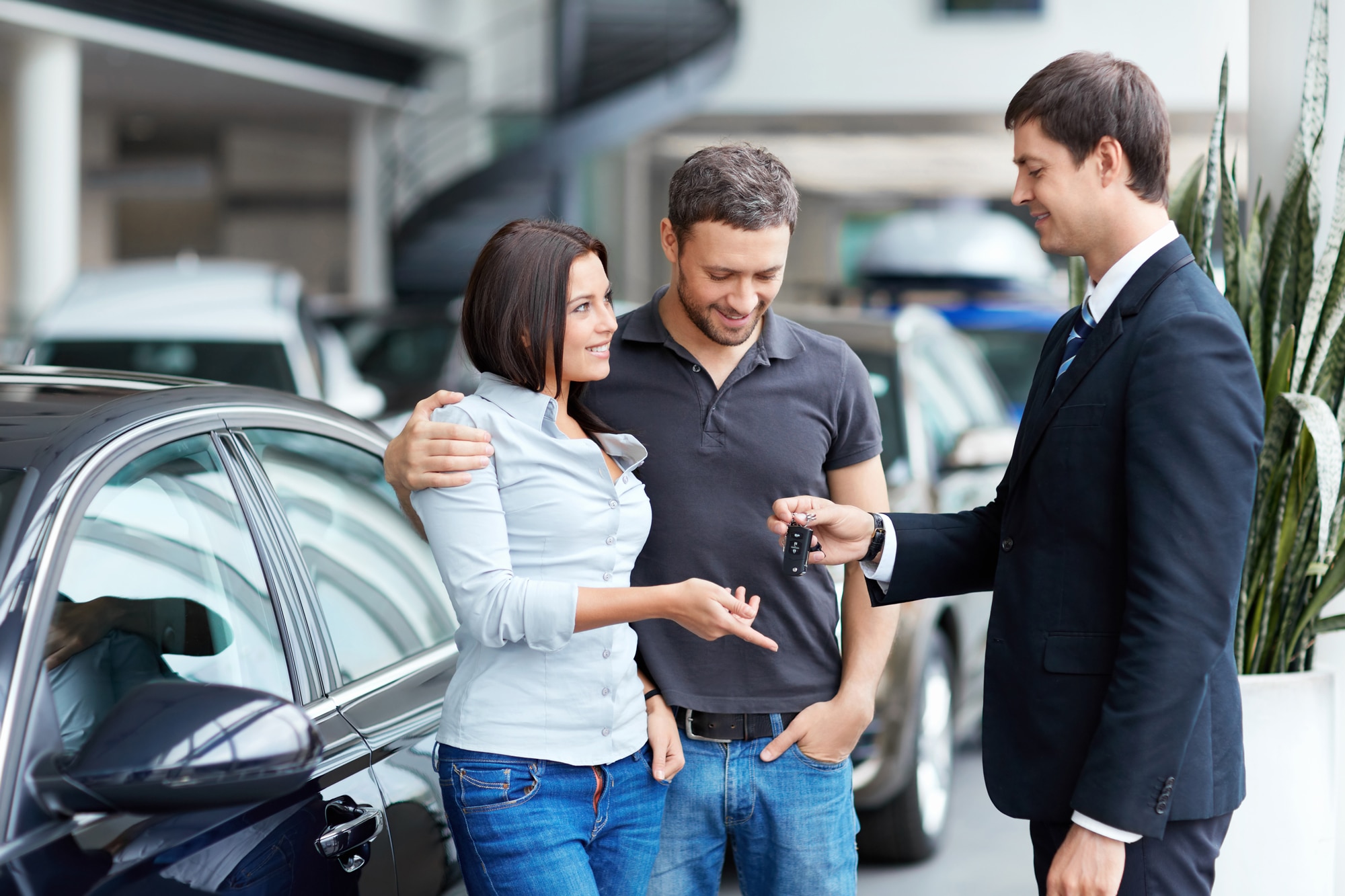 Young couple buys car and a representative hands the keys over to them