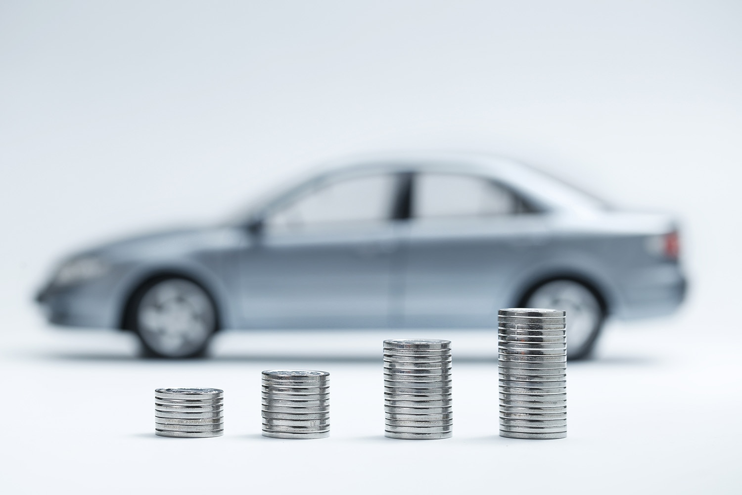 Coin stacks in front of blurred-out car in profile, background