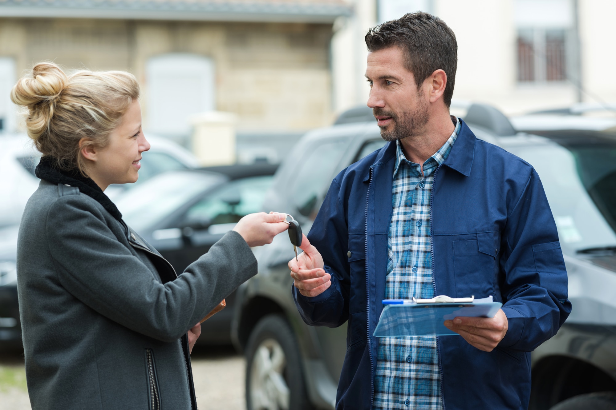 Woman handing car key over to man with clipboard