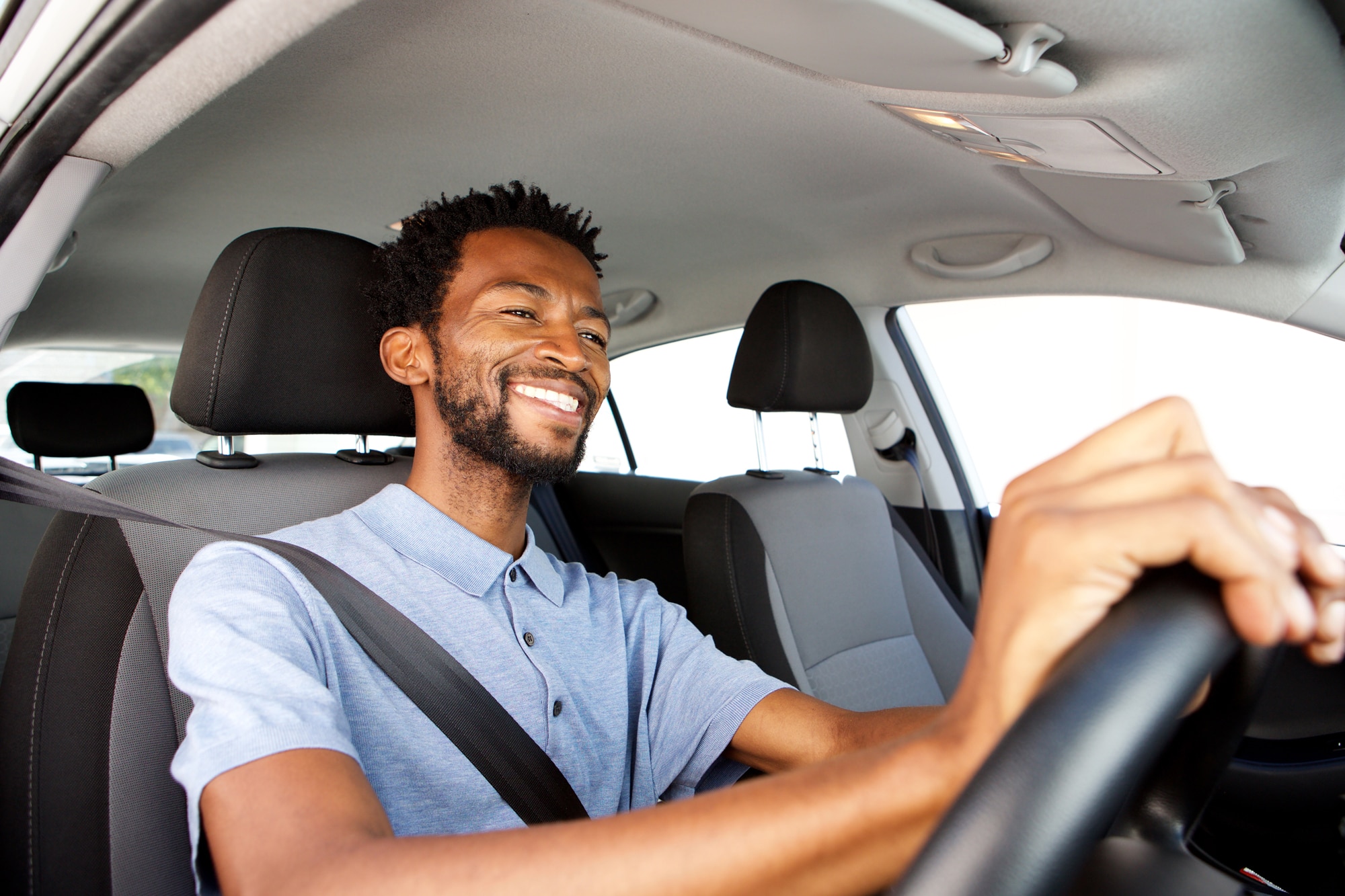 Close up side portrait of happy African American man driving car