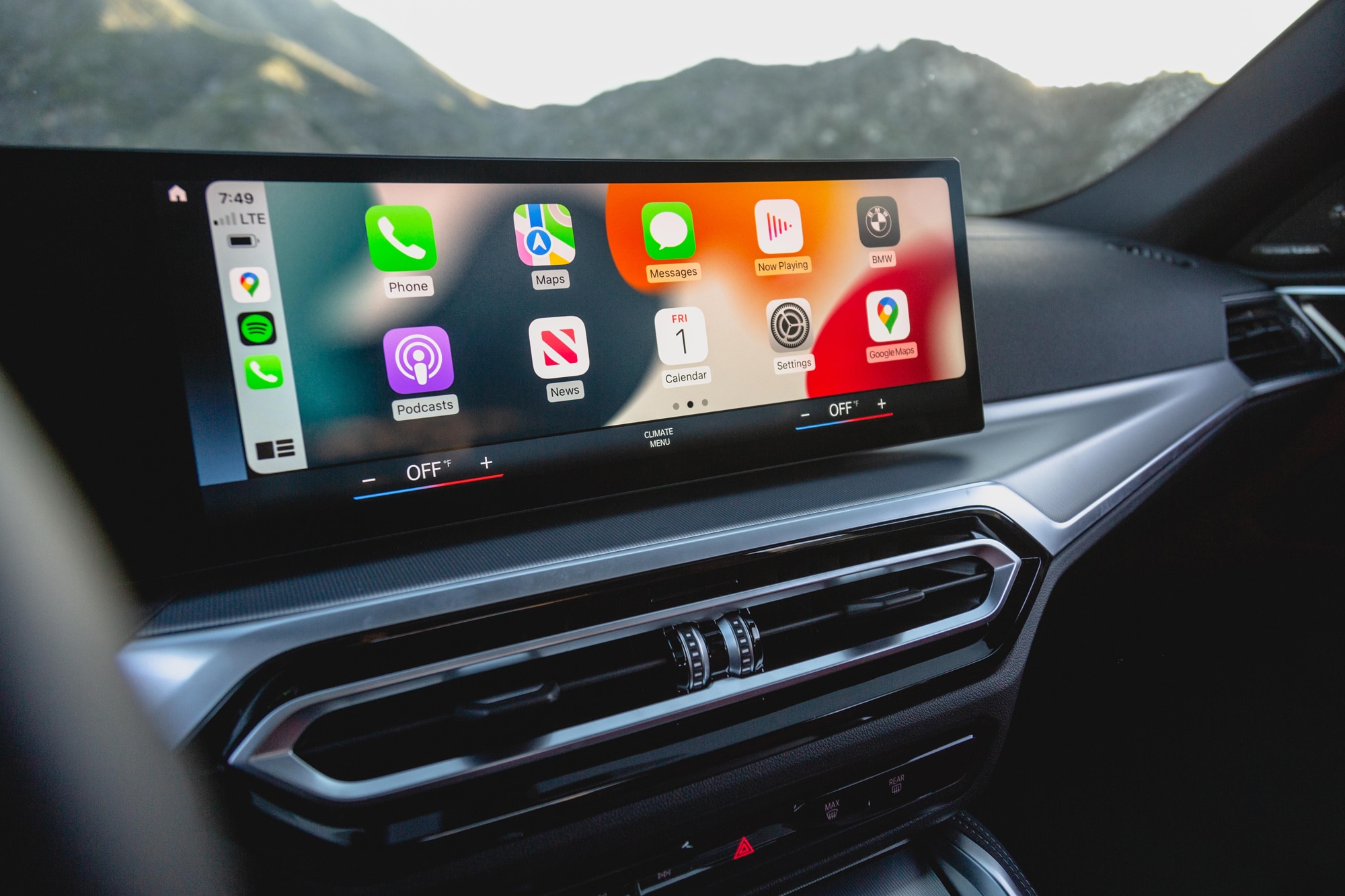 BMW i4 infotainment system showing Apple CarPlay with mountains in view