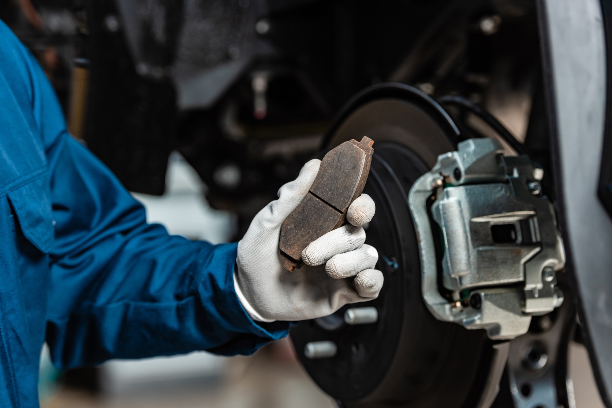 Mechanic wearing white gloves holding brake pad