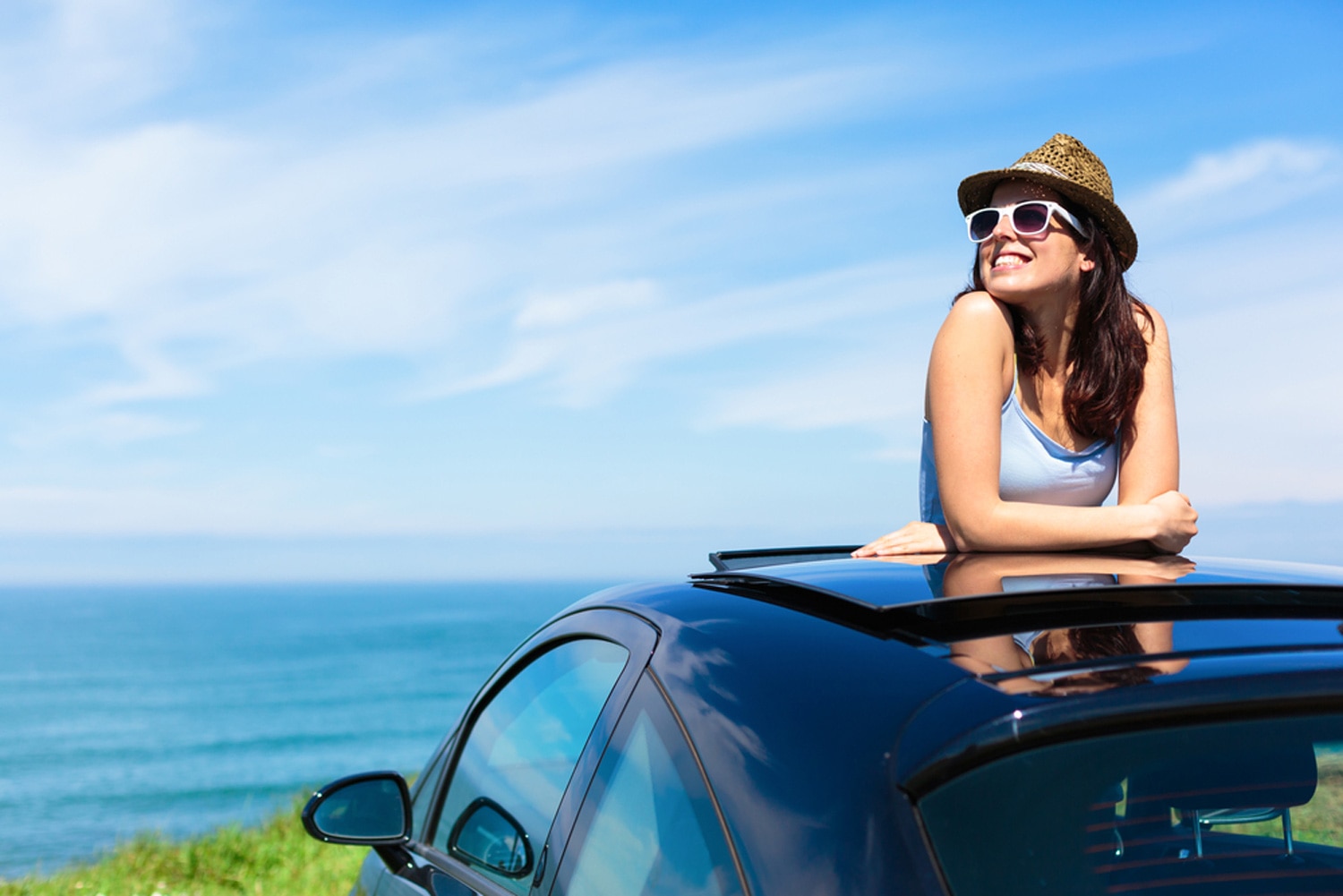 Woman smiles from sunroof of car
