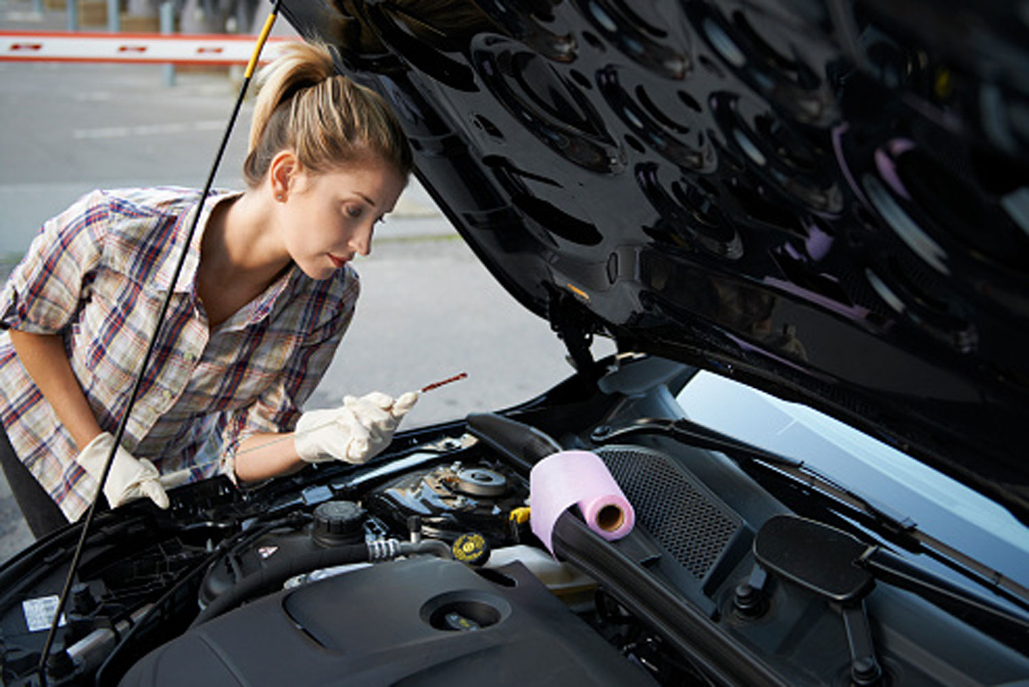 Woman checking oil under hood of car