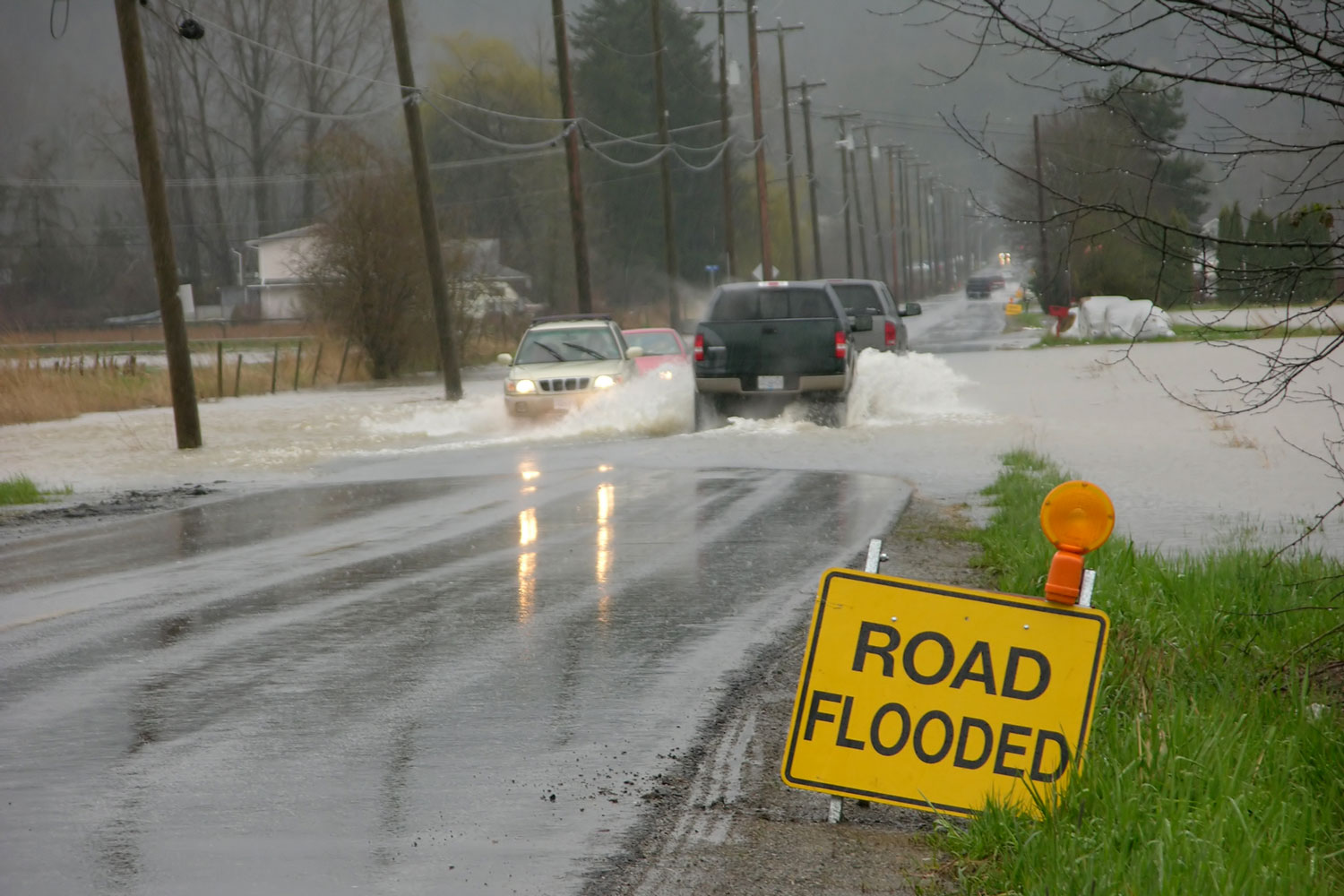 Cars in flooded road with road flooded sign