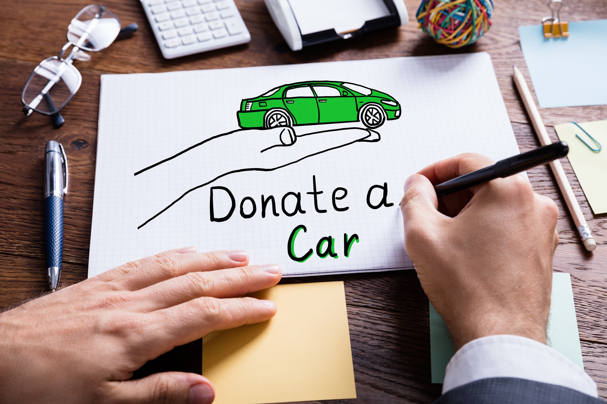 Close-up of person drawing a car for donation on a desk