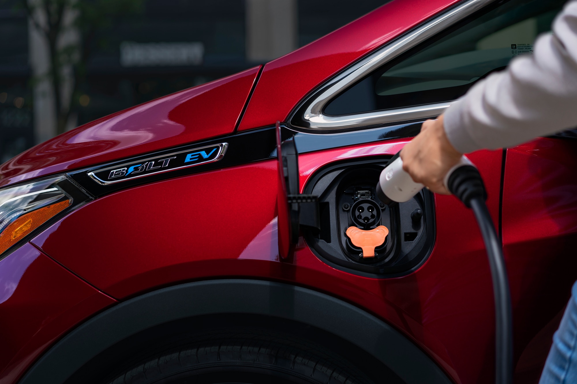 Red Chevrolet Bolt EV being plugged in to charge