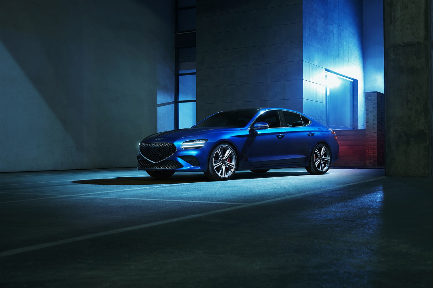 2023 Genesis G70 in blue parked by a dramatically illuminated building