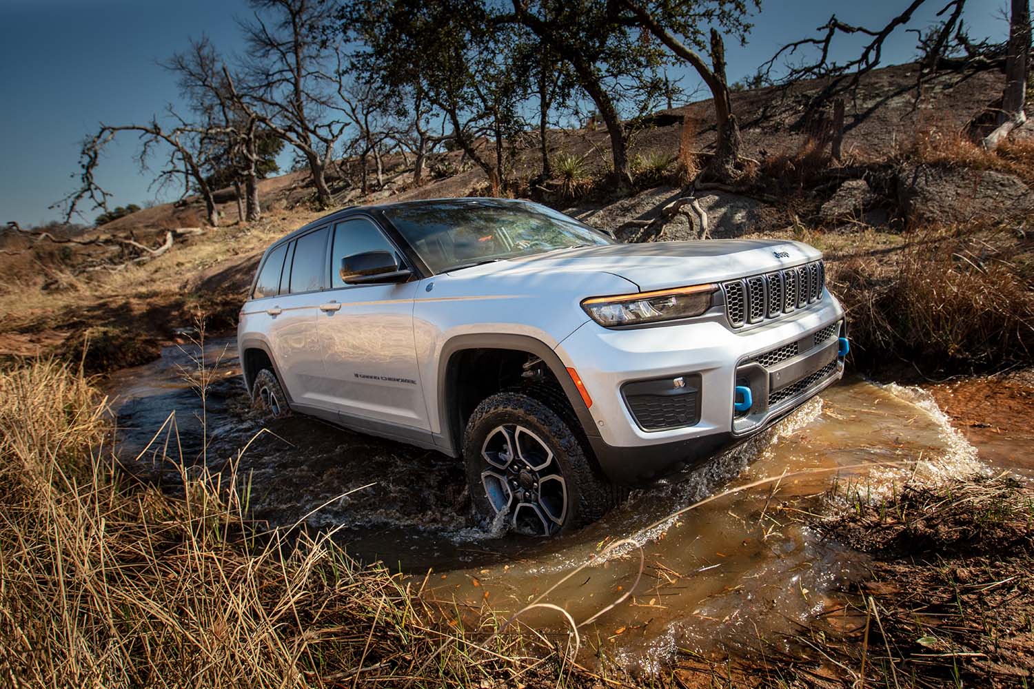 2023 Jeep Grand Cherokee 4xe in white exiting a puddle along an off-road trail