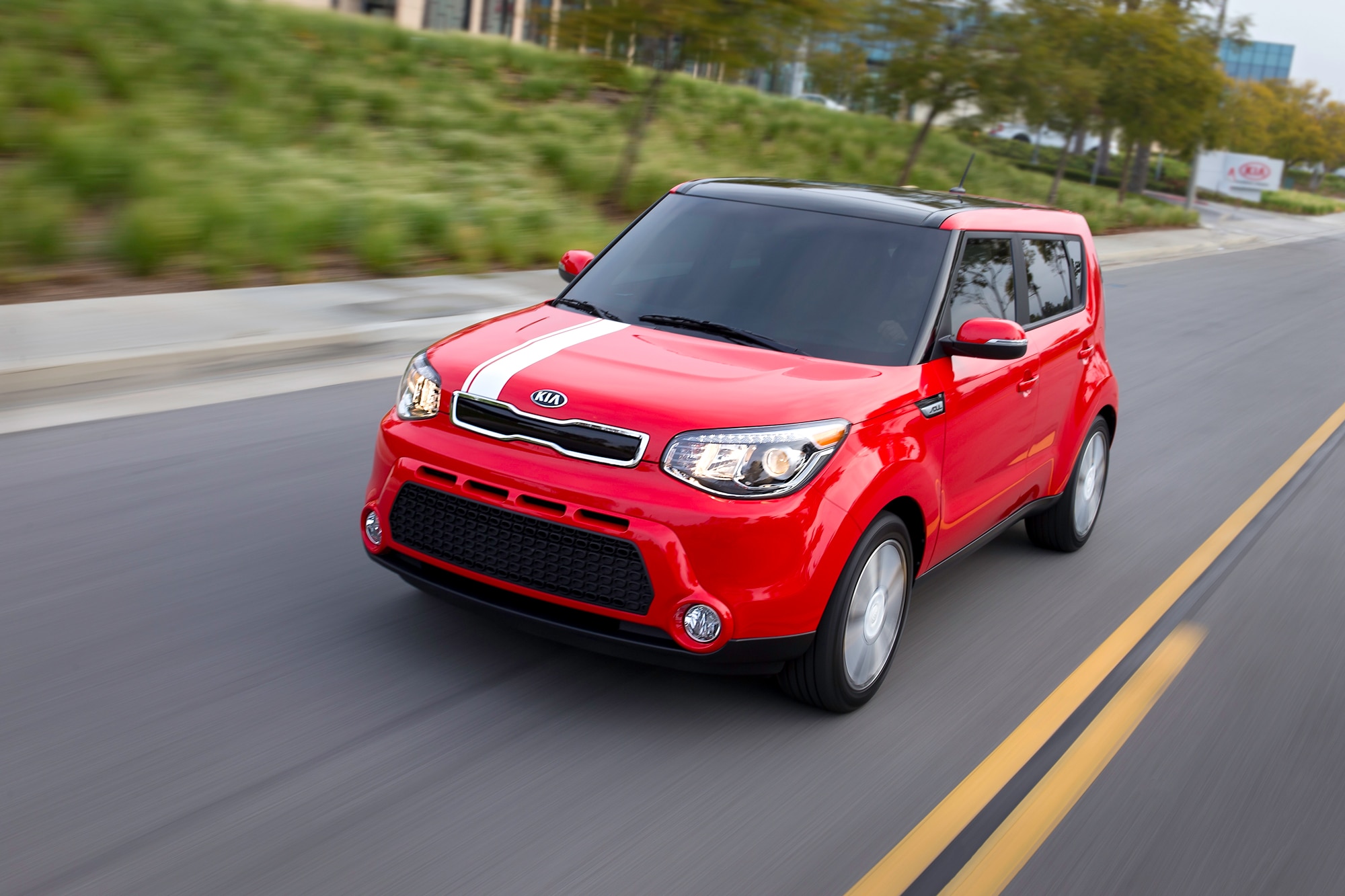 Red 2014 Kia Soul driving down highway