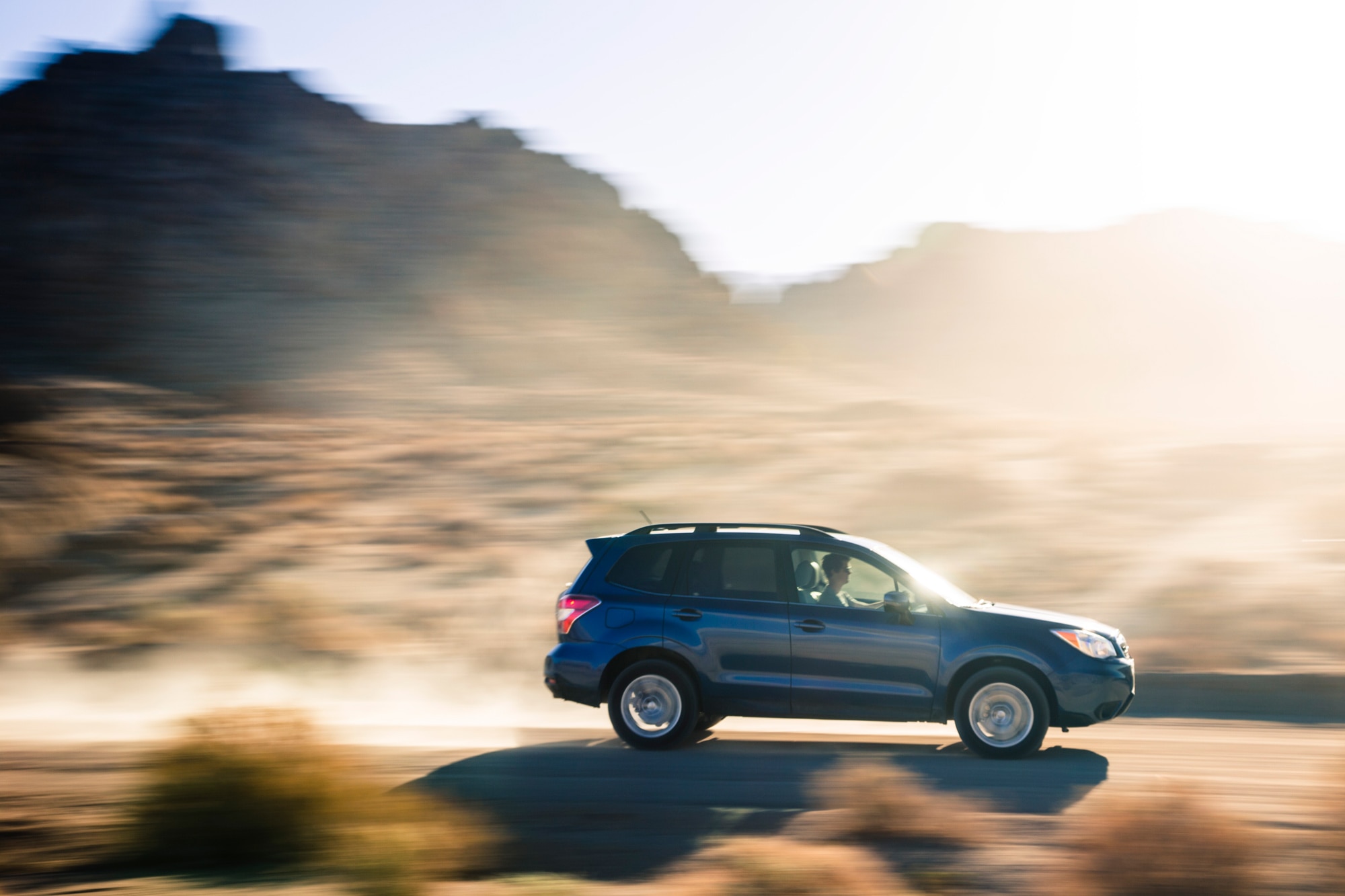 Blue 2014 Subaru Forester driving down desert road