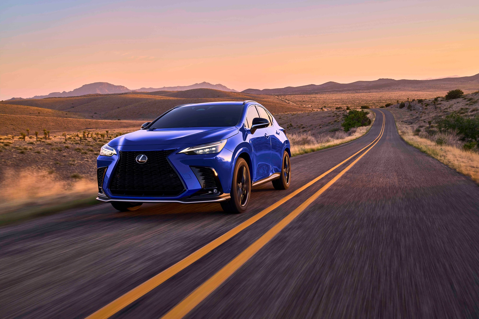 Blue 2023 Lexus NX 450H+ on the highway in the mountains