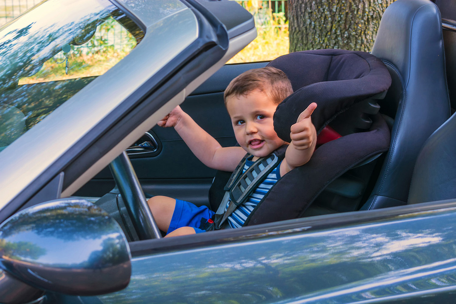 A child sits in a convertible child seat in a convertible car