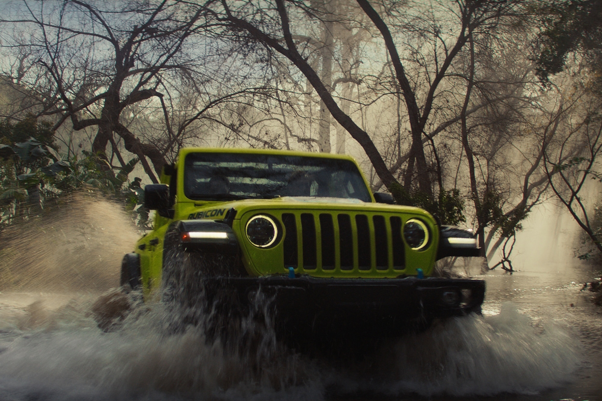 Neon Green 2023 Jeep Wrangler Rubicon 4xe driving over water in the forest