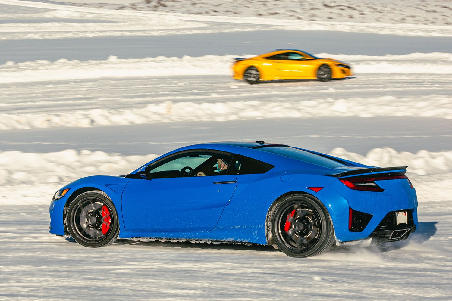 Mid-engine, exotic sports cars driving on snow