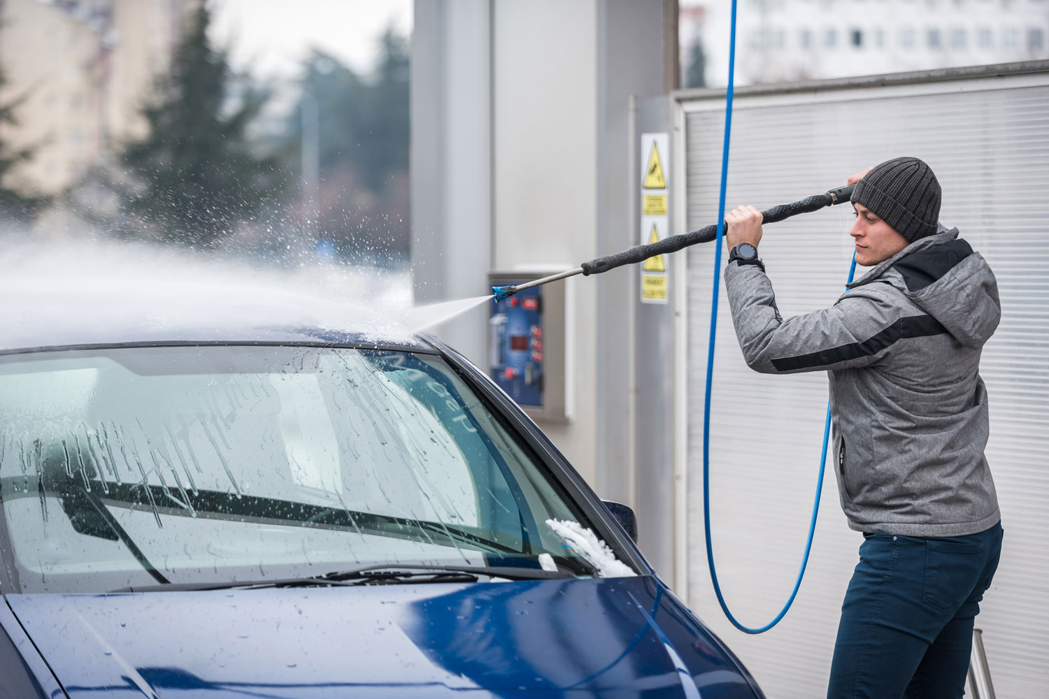 Man power washing a blue car