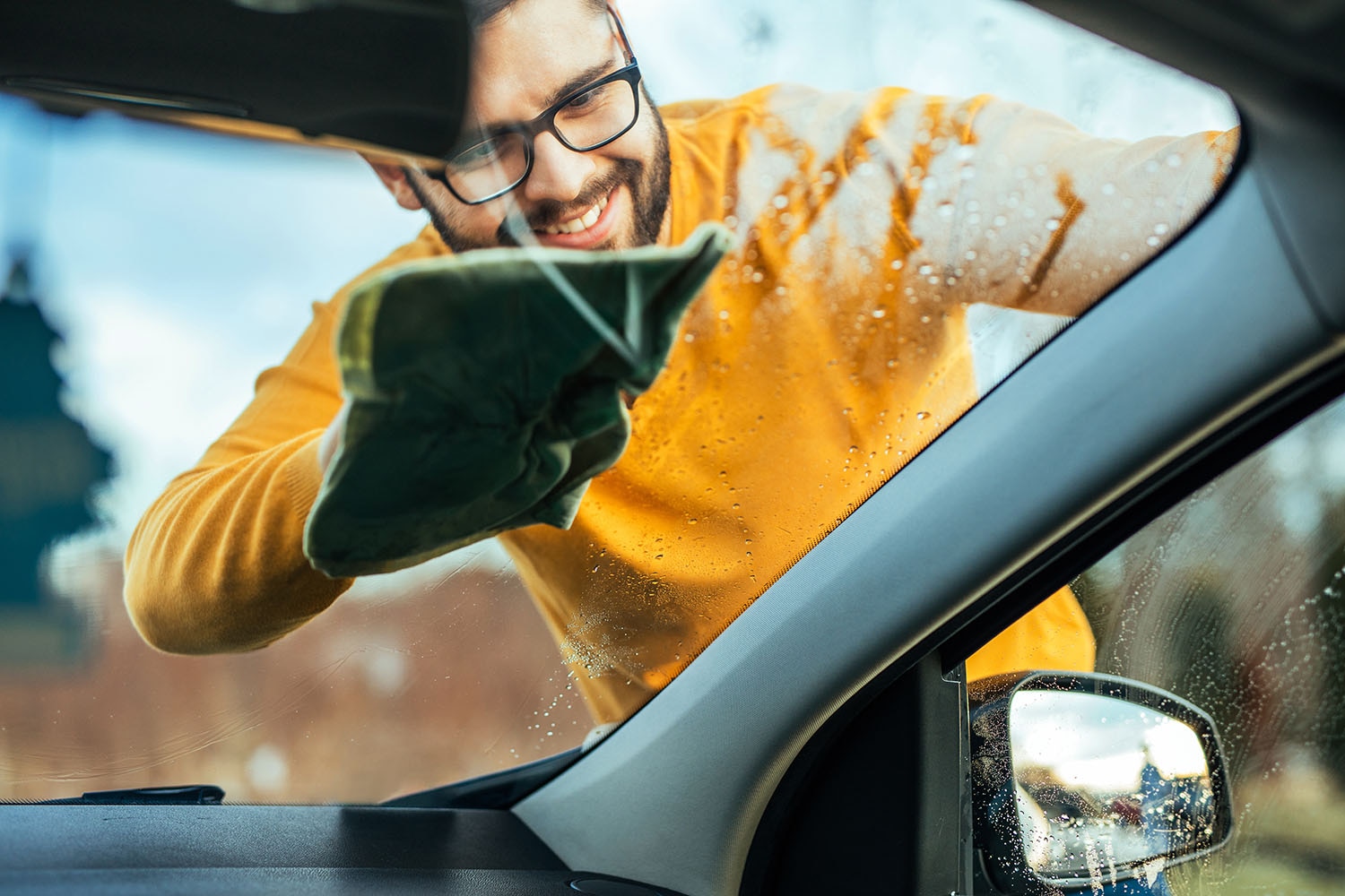 man washing windshield on car