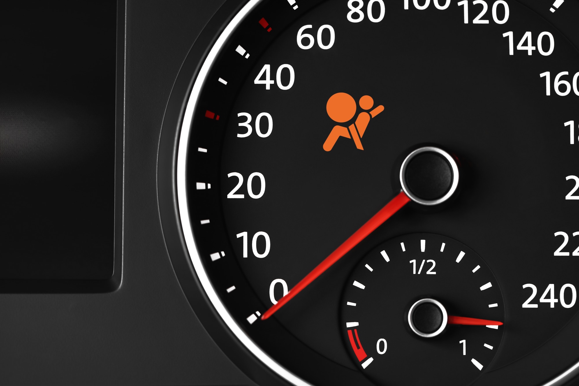 Close-up view of dashboard with orange airbag warning light on speedometer