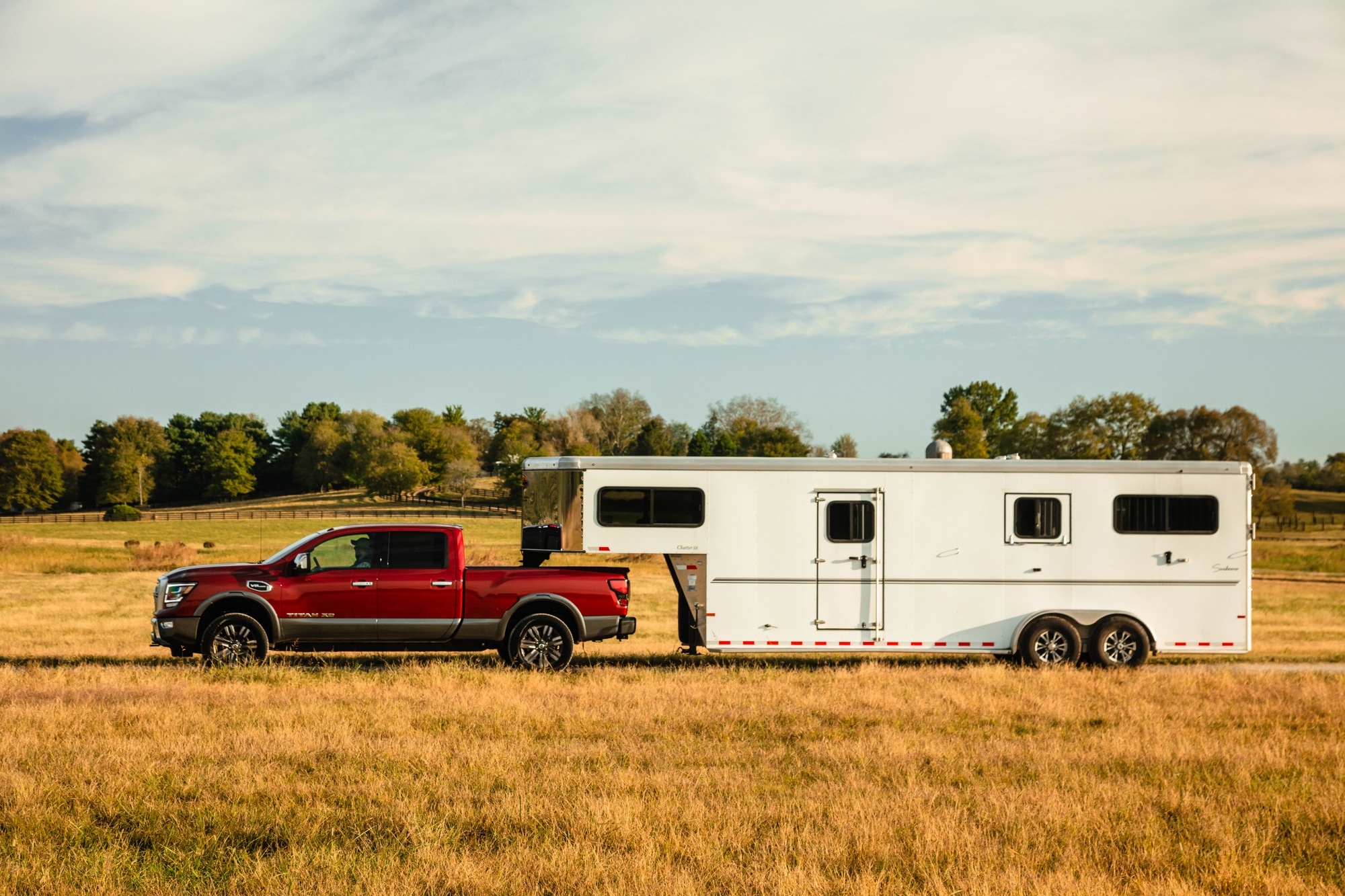 Red 2020 Nissan TITAN XD Platinum Reserve attached to a white RV in a field