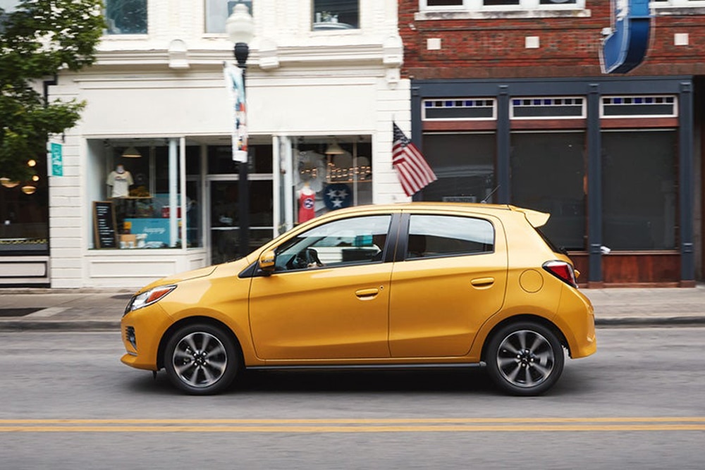 Yellow 2023 Mitsubishi Mirage side profile driving in the city
