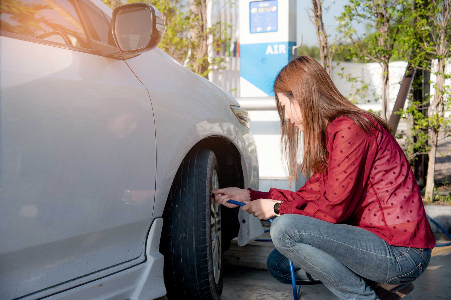 Woman checks tire pressure of car at air pump