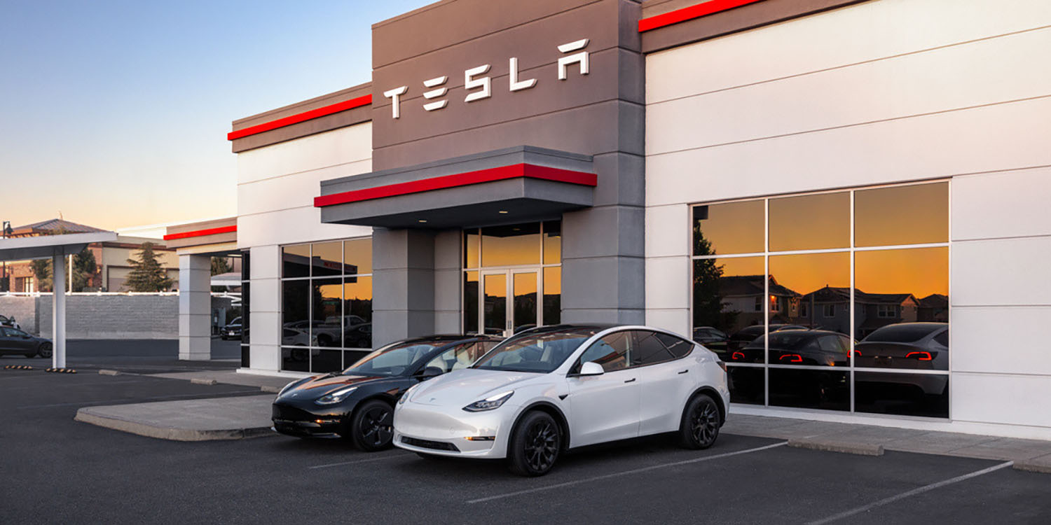 The front of a Tesla building with two EVs parked outside
