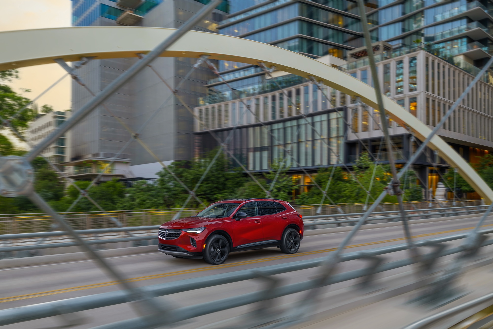 Red front 3/4 view of 2023 Buick Envision Essence in Cinnabar Metallic driving on bridge