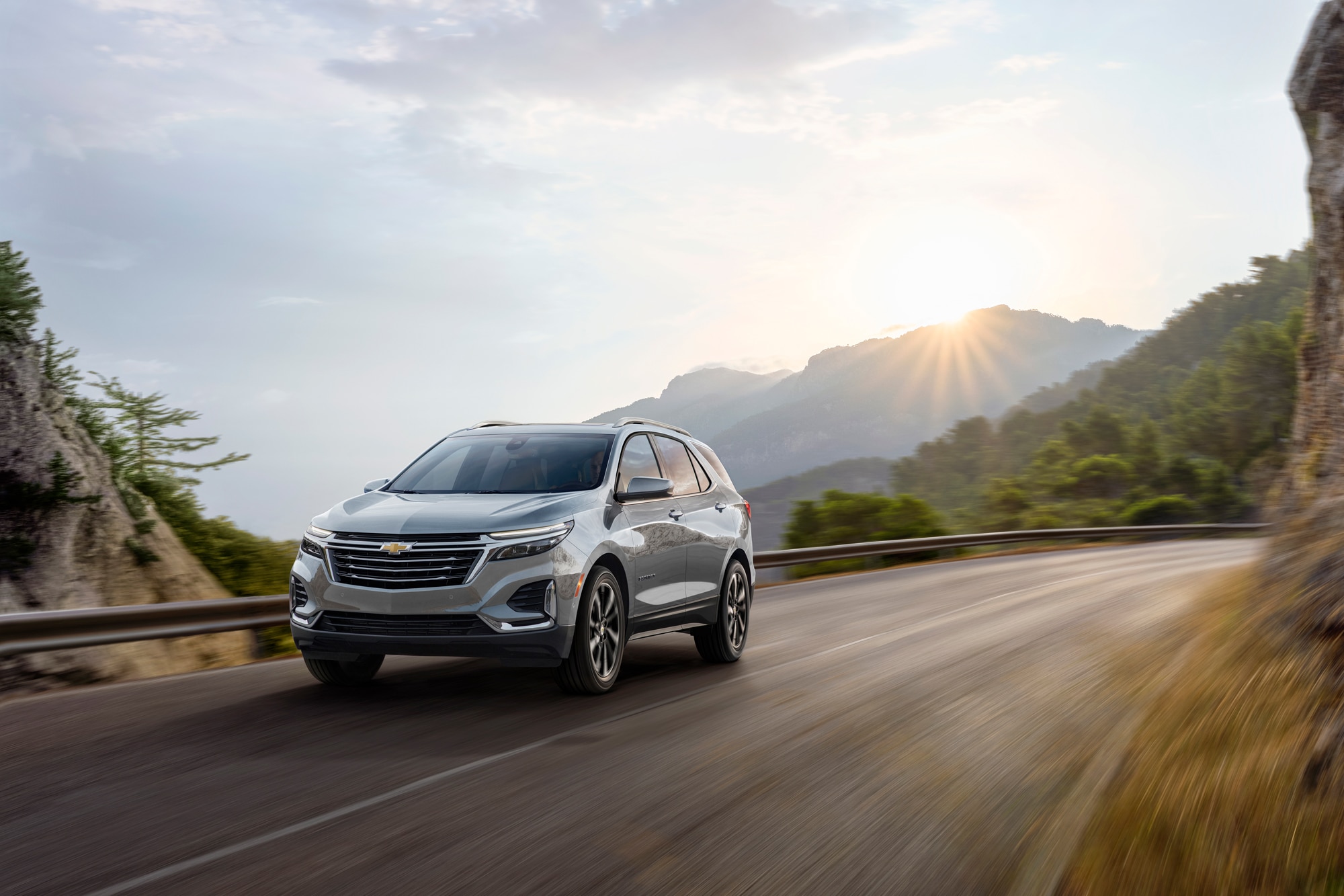Front 3/4 view of 2023 Chevrolet Equinox Premier in Sterling Gray Metallic driving on mountain road