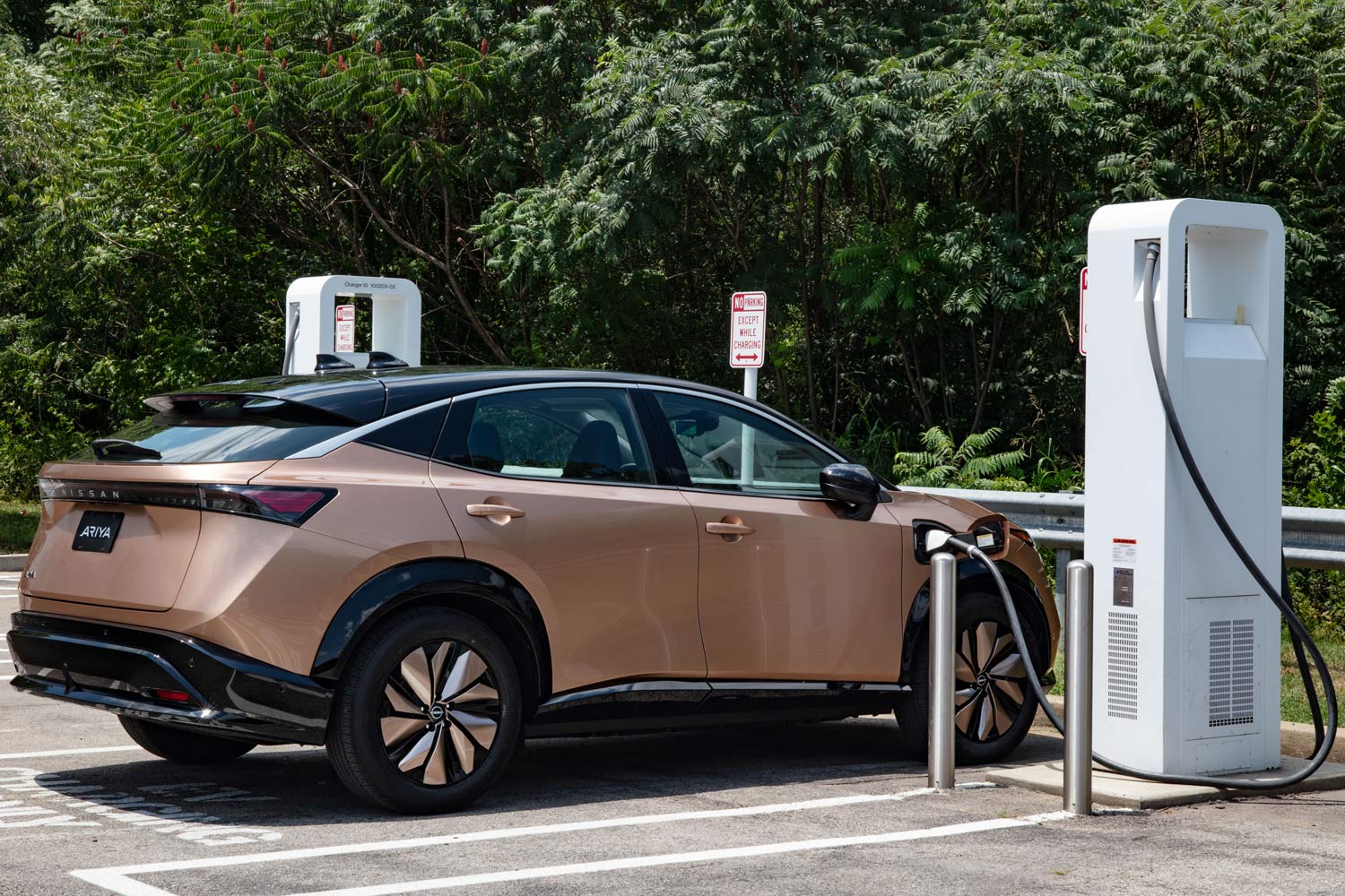 A bronze Nissan Ariya is parked at a charging station.
