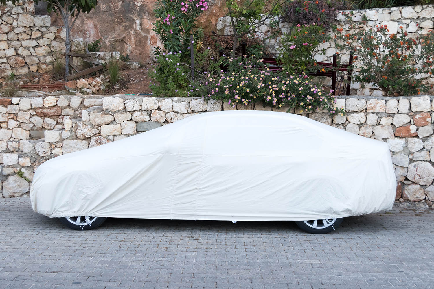 Car under cover parked next to stone wall