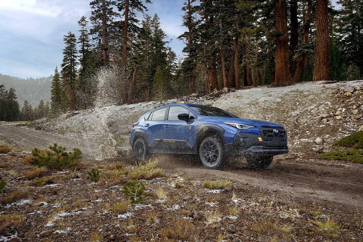 2024 Subaru Crosstrek Wilderness in blue splashing across an alpine trail