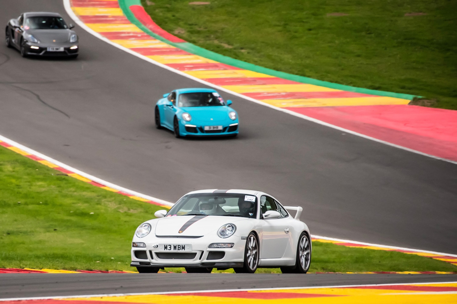 White, blue, and black Porsche navigating the turns at a racetrack.