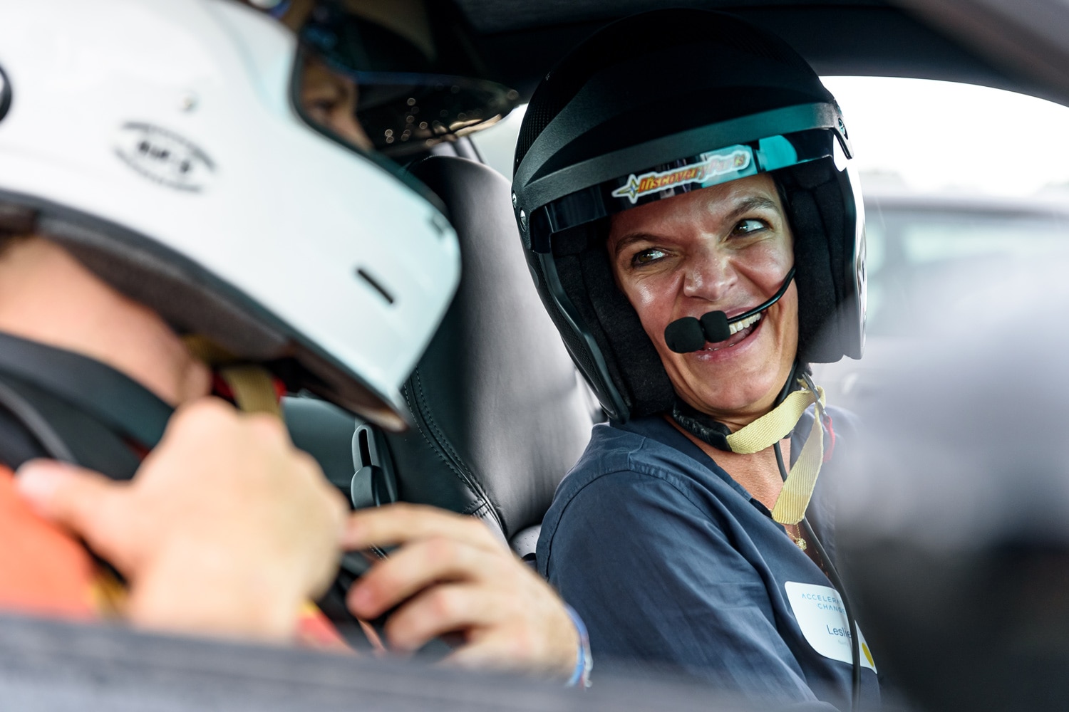 Two people wearing helmets sitting in a car.