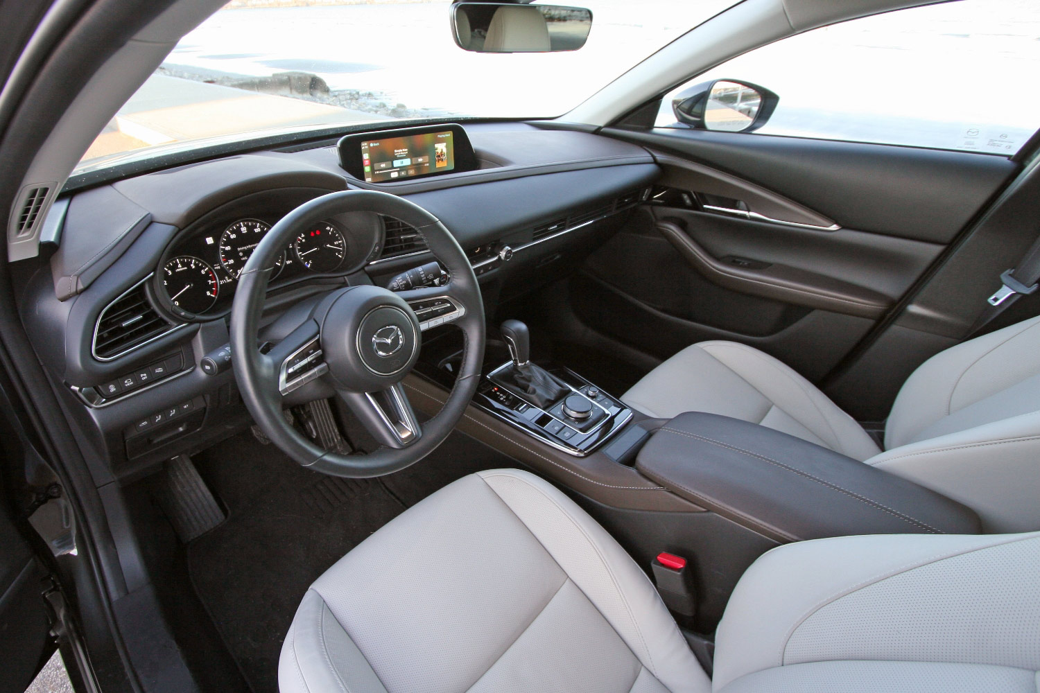 Interior of a Mazda CX-30 that shows the dashboard, steering wheel, front seats, and center console.