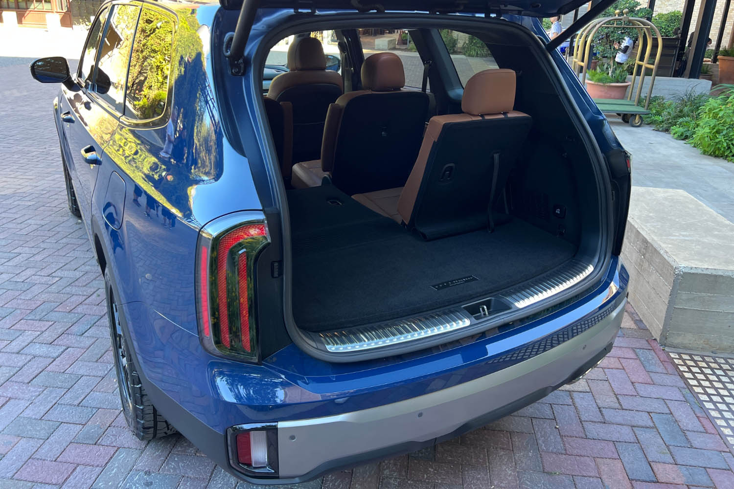 2023 Kia Telluride with rear hatch open into cargo area behind the third row of seating, with left third-row seat folded flat.