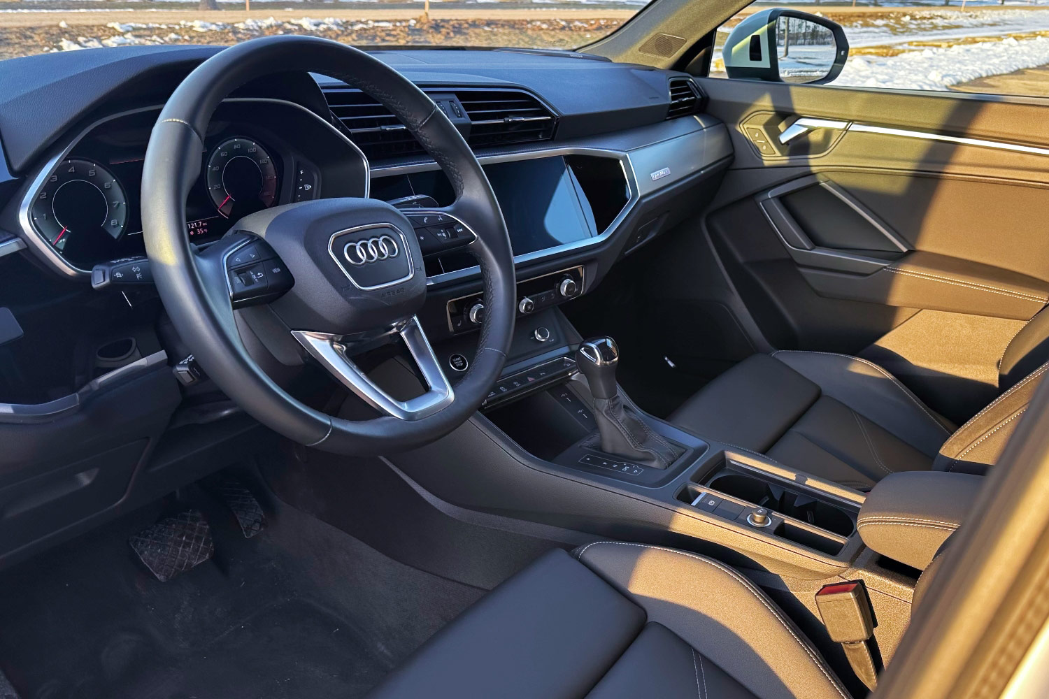 The front seats, steering wheel, dashboard, and center console of an Audi Q3.