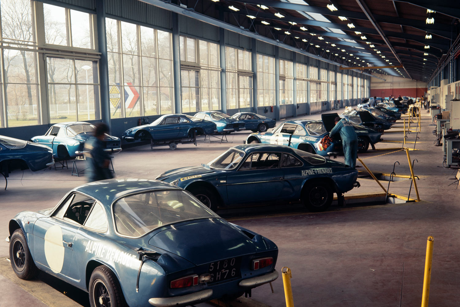 A line of several classic blue Alpine sports cars in an auto shop