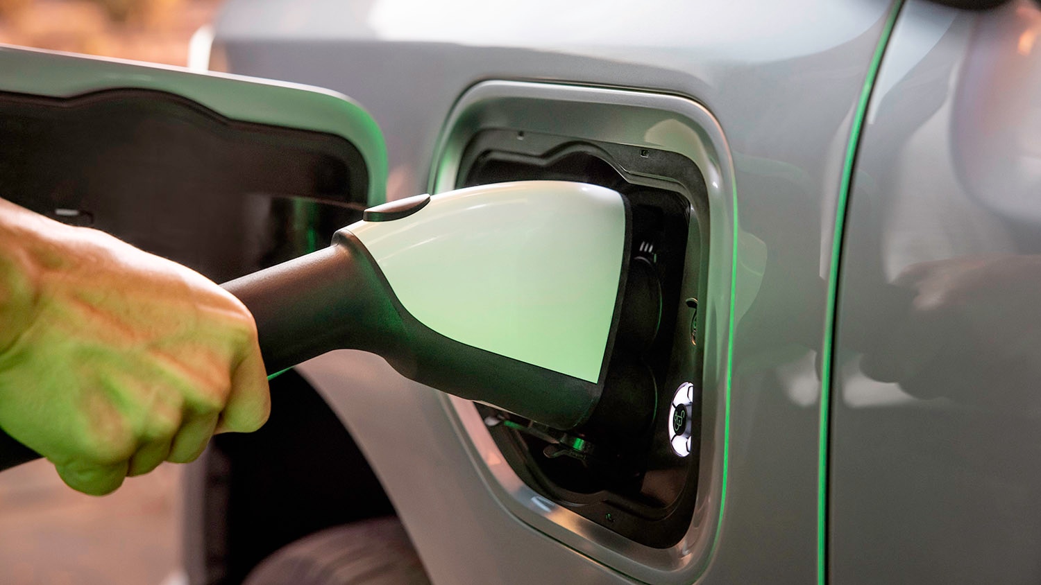 A person's hand holds an EV charging device to a Ford F-150 Lightning.
