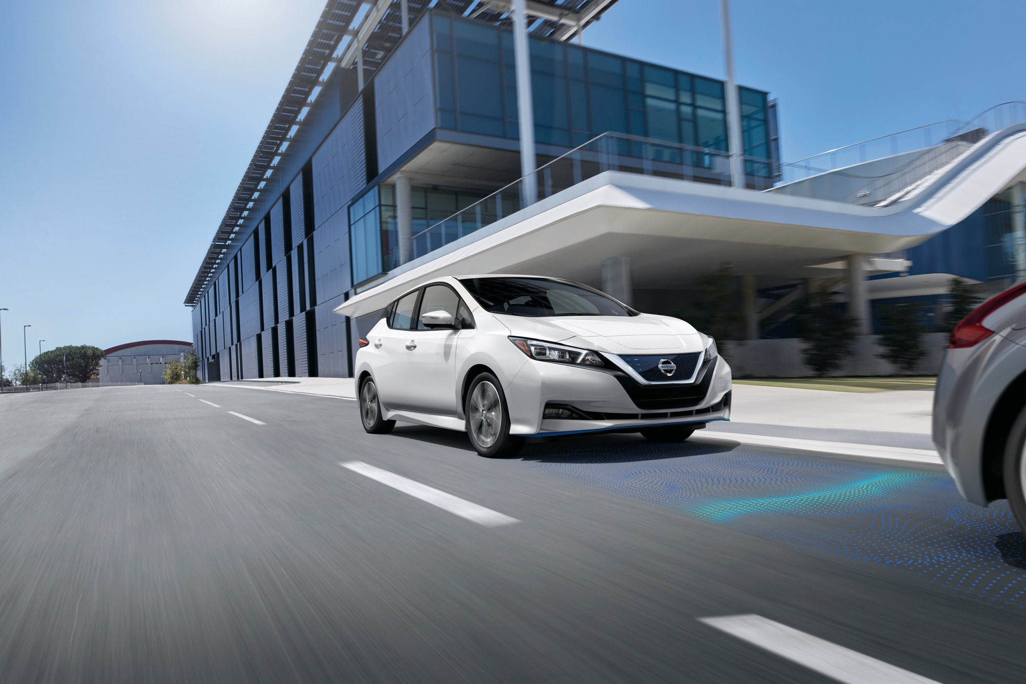 White 2022 Nissan Leaf driving down city streets