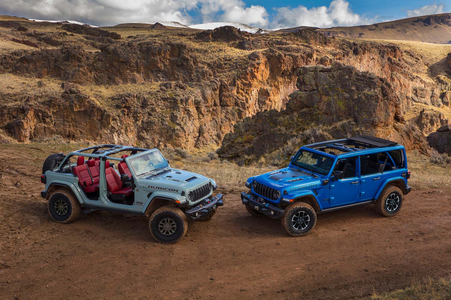 two Jeep Wrangler Unlimited models parked on dirt road