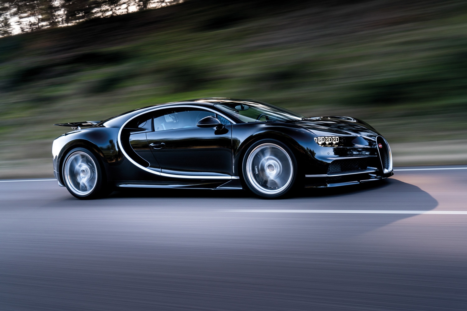 Black Bugatti being driven on a road.