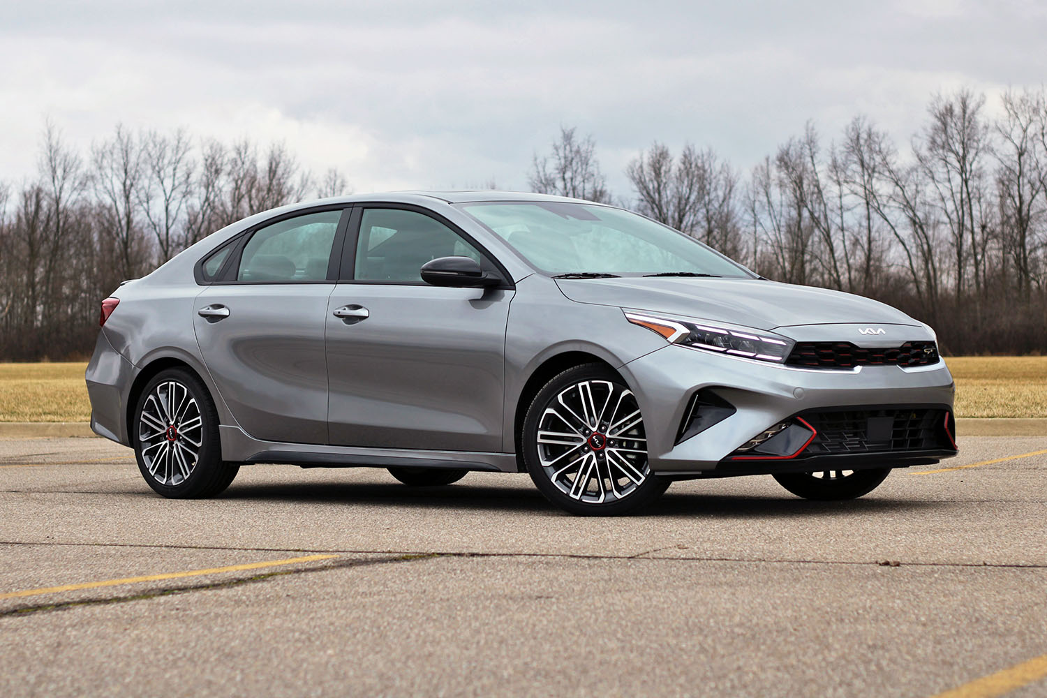 2022 Kia Forte GT in gray parked with denudate trees in the distance
