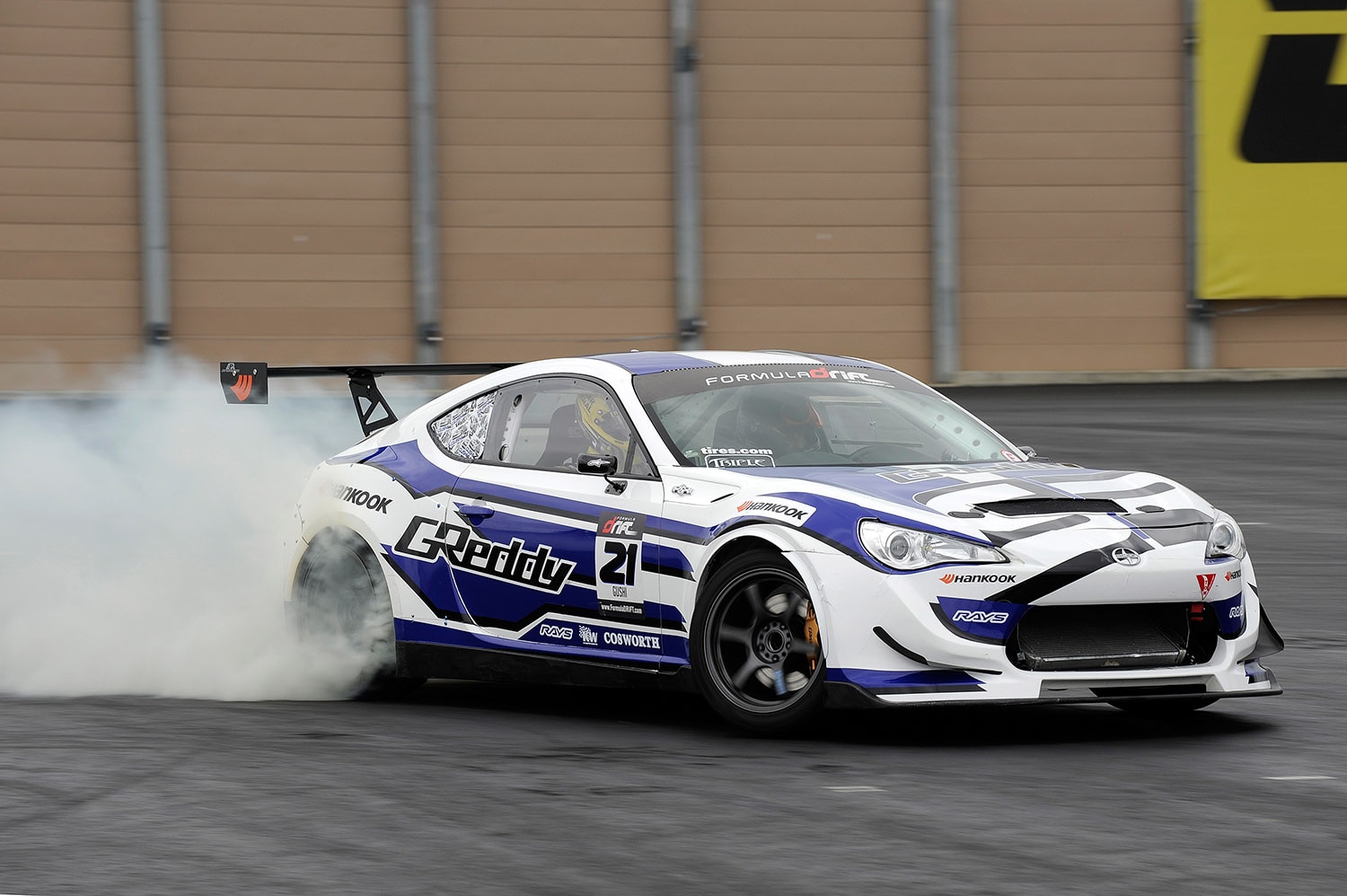 Scion FR-S in white and blue with white smoke behind it drifting around a track